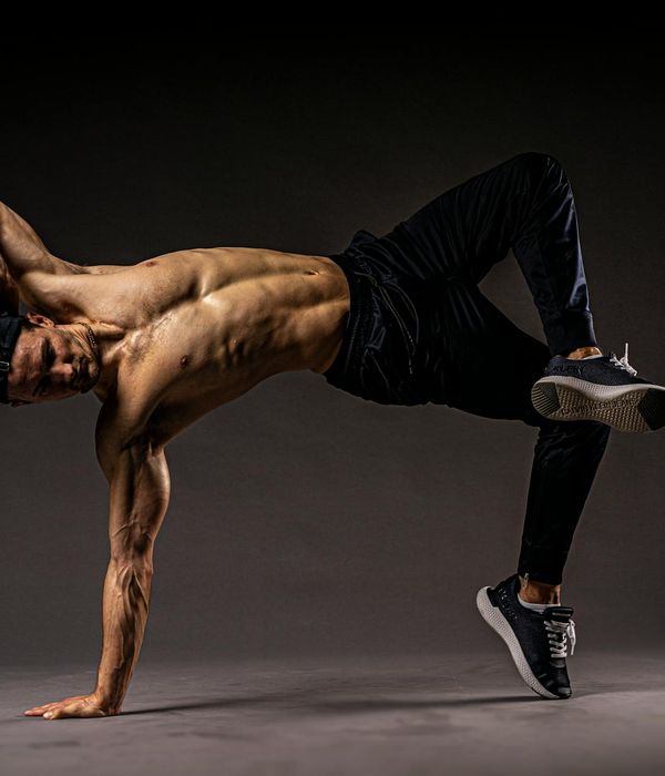 Athletic man performing controlled strength movement in dark studio